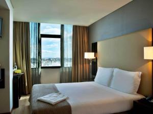 pokój hotelowy z łóżkiem i dużym oknem w obiekcie TURIM Alameda Hotel w Lizbonie