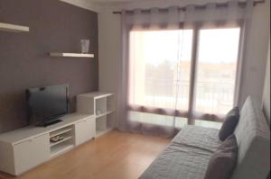 a living room with a bed and a tv and a window at Apartamento Roses in Roses