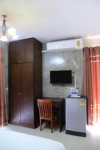 a room with a desk and a refrigerator and a television at Nava Resort in Nakhon Nayok