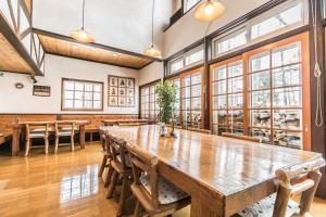 a large wooden table in a room with windows at Pension Ringo-no Ki in Hakuba