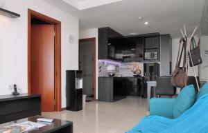 Il comprend un salon avec un canapé bleu et une cuisine. dans l'établissement Green Bay Condominium by Kevin, à Jakarta