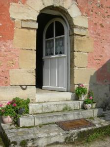 uma porta num edifício de tijolos com escadas e flores em La Ferme Rose em Cergy