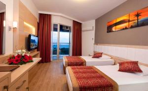 a hotel room with two beds and a television at Gardenia Hotel in Alanya