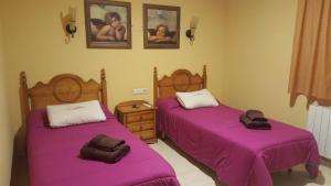 two beds in a room with purple sheets at Hotel Banyeres in Banyeres de Mariola