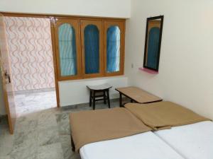 a bedroom with a bed and a table and windows at MSR Lodge in Tirupati