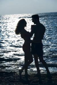 a man and a pregnant woman standing on the beach at Constantinou Bros Pioneer Beach Hotel in Paphos