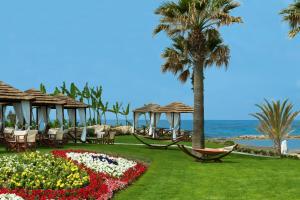 a resort with chairs and a garden with flowers at Constantinou Bros Pioneer Beach Hotel in Paphos +28 photos