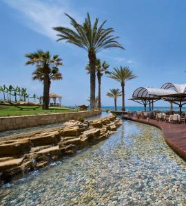 a resort pool with palm trees and a walkway at Constantinou Bros Pioneer Beach Hotel in Paphos