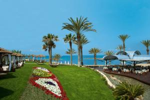 a flower garden at the beach with the ocean in the background at Constantinou Bros Pioneer Beach Hotel in Paphos