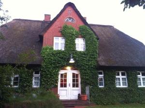 une maison recouverte de lierre avec une porte blanche dans l'établissement Gästehaus Kapitän Jan Ricklefs, à Nebel