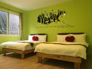 魚池鄉的住宿－卉芯蘭園休閒民宿，绿色客房的两张床,墙上有心