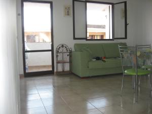 a living room with a green couch and some chairs at Appartamento al mare, Isola blu in Marzamemi