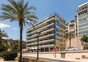 a tall building with a palm tree in front of it at Flats Friends Atlantida in Benidorm