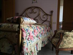a bedroom with a bed with a floral quilt and a chair at B&B Mirella in Citta' Sant'Angelo