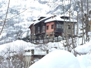 una casa en una colina nevada con nieve en Complejo Turístico L'oteru, en Caleao