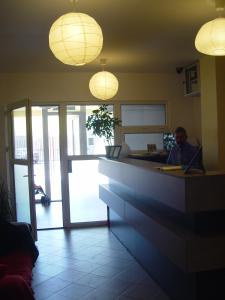 un hombre sentado en un escritorio en una habitación con luces en Hotel Astra, en Brasov