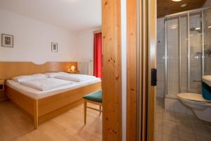 a bedroom with a bed and a bathroom with a shower at Hotel Lipeter & Bergheimat in Weissensee