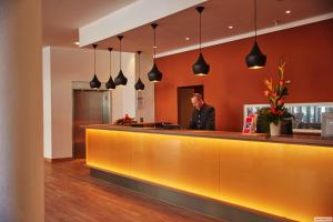 a man standing at the reception desk of a hotel at H4 Hotel Hamburg Bergedorf in Hamburg