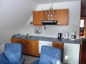 a kitchen with a sink and two blue chairs at Gästehaus Kapitän Jan Ricklefs in Nebel