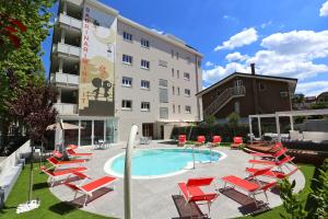 Hotel Sabrina Rimini في ريميني: مسبح وكراسي صالة حمراء ومبنى
