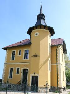 un grand bâtiment jaune avec une tour d'horloge dans l'établissement Anna Villa, à Keszthely