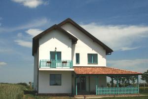a white house with a balcony on top of it at Frăgăria in Zimandcuz