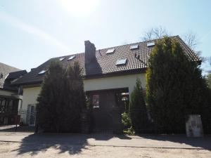 a house with a black roof and two trees at Dom Artusa in Ustka
