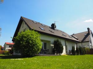 una casa blanca con techo negro y patio en Dom Artusa en Ustka
