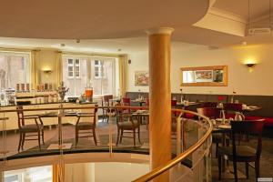a restaurant with tables and chairs in a room at Sunday Hotel Stade Herzog Widukind in Stade