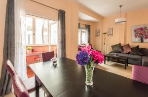 Apartamentos El Rastro في مدريد: غرفة معيشة مع طاولة مع إناء من الزهور عليها