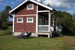 Un uomo seduto su una panchina di fronte a una casetta di Purolomat a Merikarvia