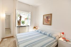 una camera bianca con un letto e una finestra di La Villetta a Portovenere