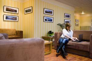 a woman sitting on a couch with a laptop at VTF Le Domaine des Puys in Saint-Sauves- dʼAuvergne