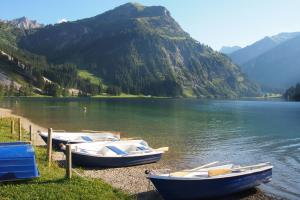 tre barche sulla riva di un lago con una montagna di Haus Bergwelt a Grän
