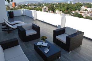 einen Balkon mit 2 Stühlen und einem Tisch auf dem Dach in der Unterkunft Eco Hotel Guadalajara Expo in Guadalajara