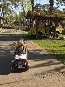 a little girl riding a toy scooter down a sidewalk at Ameba Resort in Mielno +66 photos