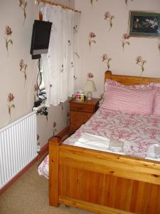a bedroom with a wooden bed and a television at The Clochfaen in Llangurig