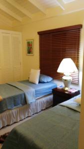 a bedroom with a bed with a lamp and a window at Relax Villa in Ocho Rios