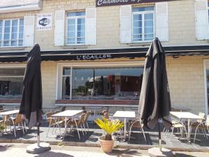 a group of tables and umbrellas in front of a restaurant at L'Ecailler in Ouistreham