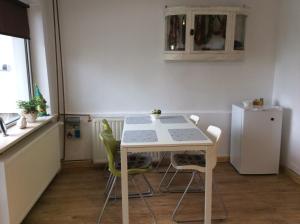 a kitchen with a white table and chairs and a refrigerator at Pracownia pod 7 in Szczecin