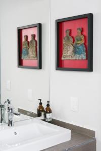 two framed pictures on the wall above a bathroom sink at La Palomilla Bed & Breakfast in Mexico City