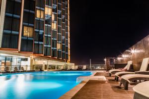 a hotel swimming pool at night with chairs at Azalaï Hôtel Abidjan in Abidjan