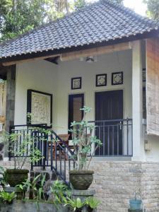 a small house with a gate and a balcony at Latugu Homestay Ubud in Ubud