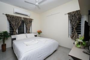 a bedroom with a white bed and two windows at Krishna Vibe Service Apartment in Tiruchchirāppalli