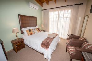 sypialnia z łóżkiem, krzesłem i oknem w obiekcie Sunset Manor Guest House w mieście Potchefstroom