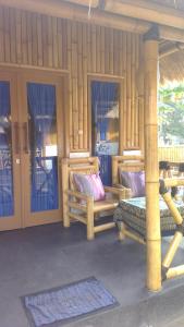 a house with a porch with two benches and windows at Tua Tua Keladi Bungalows in Gili Islands
