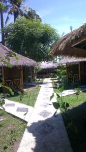 una pasarela con algunas sombrillas de paja en una playa en Tua Tua Keladi Bungalows, en Gili Air