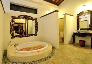 a bathroom with a tub with a mirror and a sink at Puri Mas Boutique Resort & Spa in Senggigi