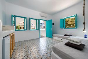 a room with two beds and a kitchen with blue windows at Nissia Beach Apartments & Suites in Kamari