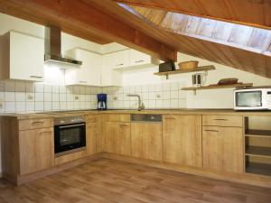 a kitchen with wooden cabinets and a sink and a microwave at Ferienhof Landhaus Michael in Böbrach